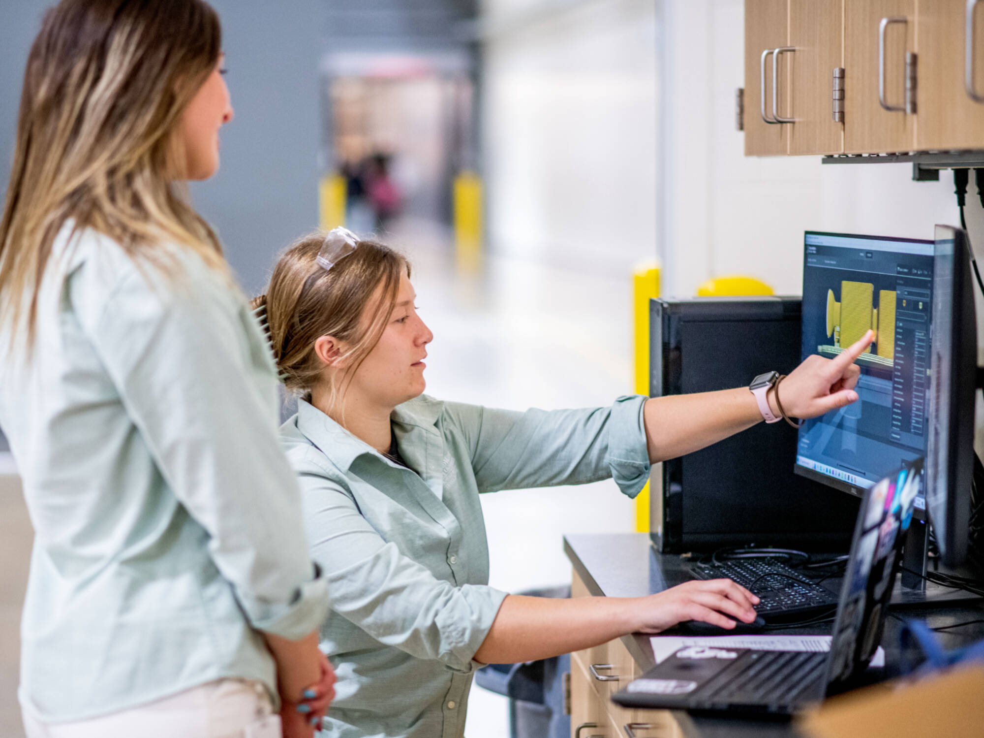 From left, Matthew Hartwell, Hailey Siwek and Cara Franke, members of the aMDI team, work on a computer near the new 3DXTECH Gearbox inside the Shape Corp Innovation Design Center